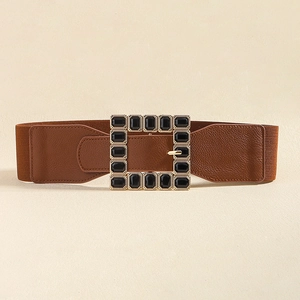 Detail of a brown elastic waist belt featuring a square gold buckle with black faux gems
