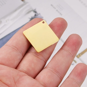 Handheld view of a 25mm square gold stainless steel pendant with hole for DIY jewelry