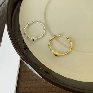 Detail of silver and gold adjustable cross rings on a minimalist ceramic display plate