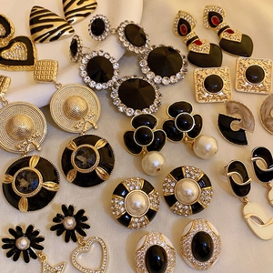 Detailed close-up of various vintage black and gold earrings with pearls and crystals