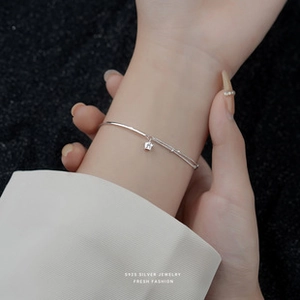 Close-up of S925 sterling silver star charm bracelet on wrist with elegant white shirt cuff