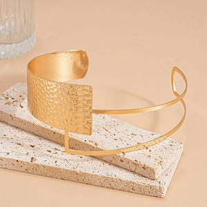 Macro detail of golden hammered metal choker on a minimalist stone pedestal display