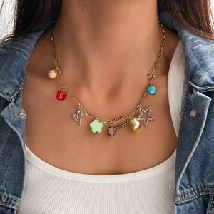 Close-up of bohemian pendant necklace with heart, flower and colorful beads on gold chain