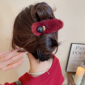 Detailed view of a burgundy plush hair claw clip with a lucky gold charm on hair