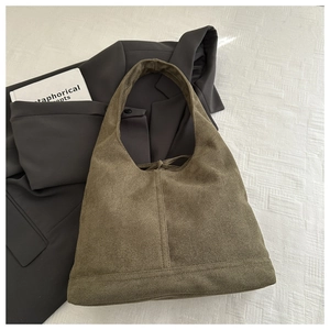 Flat lay of brown suede tote bag on white texture with gray blazer and book detail