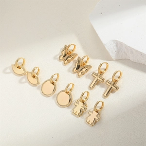 Dettaglio di orecchini a cerchio placcati oro 18K con ciondoli a farfalla e croce zircone