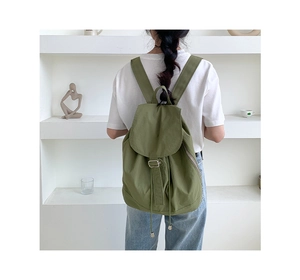 Vista posteriore dettagliata di uno zaino in nylon verde scuro con coulisse su modella