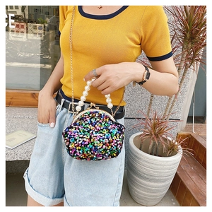 Street style view of a colorful sequin shell bag with a pearl handle and gold chain