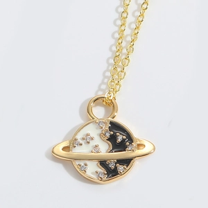 Detailed view of golden planet pendant with black and white enamel and sparkling rhinestones