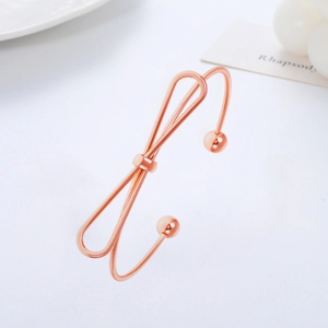 Polished rose gold open bangle featuring a minimalist bow design and spherical ends