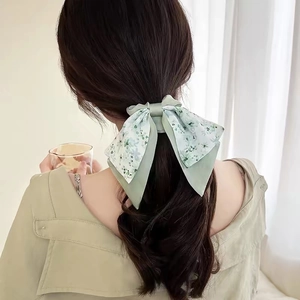Floral bow scrunchie with light green print shown on a low ponytail ponytail hairstyle