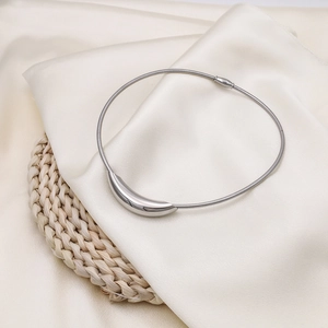 Close-up of a silver polished curved metal pendant on a snake bone chain necklace