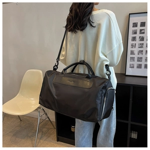Rear view of a model carrying a large black nylon sports duffel bag with shoulder straps