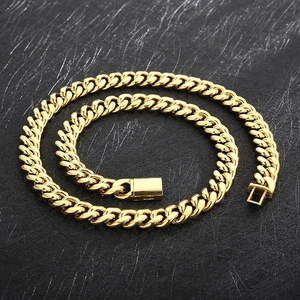 Detail of gold Cuban link chain necklace with secure box clasp on black background