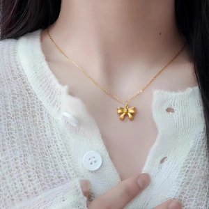 Elegant gold bow pendant necklace for women worn on neck with white knit cardigan
