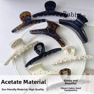 Detail of large acetate hair claws with colorful rhinestones on a white ceramic plate