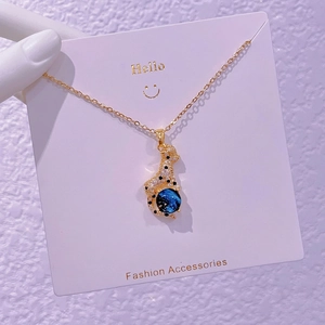 Dettaglio della collana leopardata dorata con zirconi e una perla blu dal design cosmico