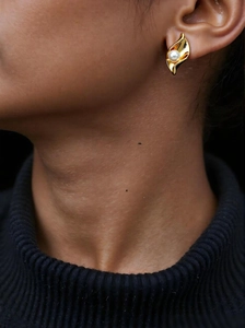 Detailed view of elegant gold pearl earring worn on ear with wave design and white pearl
