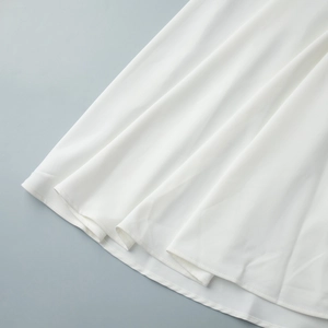 Gros plan sur l'ourlet d'une robe blanche élégante en tissu drapé de haute qualité
