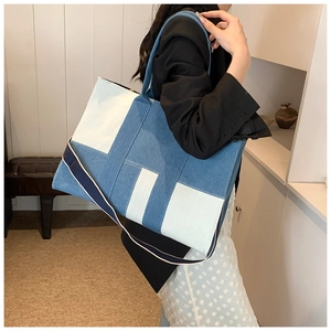 Detail of blue denim and white canvas patchwork tote bag with wide fabric strap