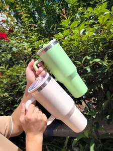 Close-up of insulated light green and pink stainless steel tumblers with sturdy handles