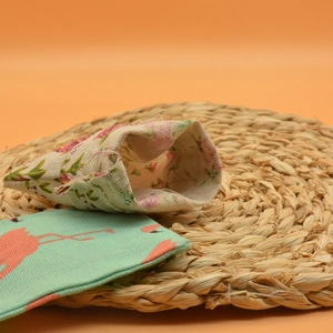 Close-up of floral and flamingo patterns on cotton drawstring sachets on a woven mat