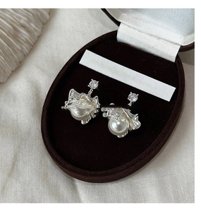 Detailed close-up of pearl earrings with zircon stones in a luxury brown velvet box