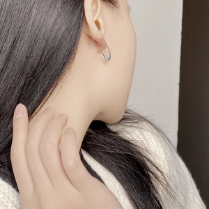 Polished silver U-shaped hoop earring shown in a professional close-up on model ear