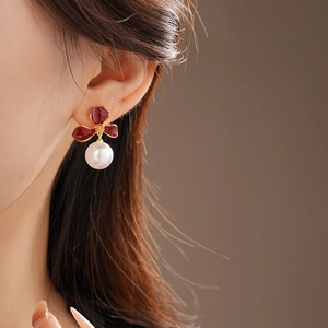 Close-up of elegant red flower pearl earrings worn by a model in a vintage French style