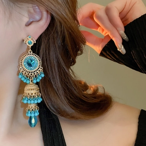 Detailed close-up of vintage golden fringe earrings with blue gemstones and jhumka beads
