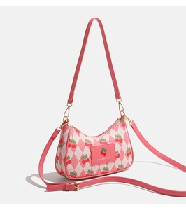 Détail du sac bandoulière matelassé rose avec imprimé cerises et détails dorés