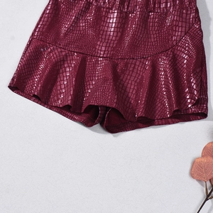 Macro view of burgundy faux leather skirt showing crocodile embossing and ruffle hem details