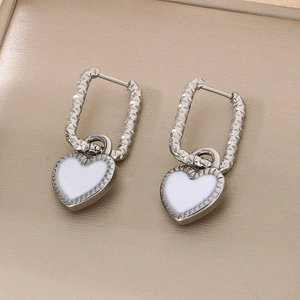 Vue détaillée de boucles d'oreilles cœur en argent avec émail blanc et fini ondulé