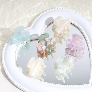 Elegant marbled acetate hair claws in pastel colors displayed on a heart-shaped mirror