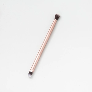 Dual-ended rose gold makeup brush with black and white bristles for blending and eye shadow