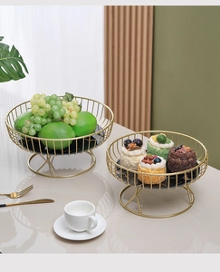 Close-up of gold iron fruit baskets with black marble base holding grapes and cakes