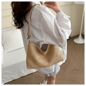 Detail of woven straw tote bag featuring leather shoulder strap with knot accent