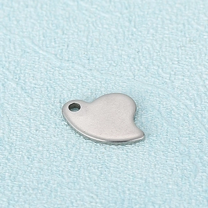 Polished gold stainless steel heart pendant on a light blue textured background
