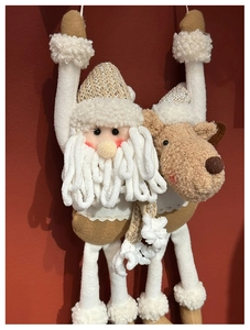Detail of plush Santa and Reindeer hanging ornaments with knitted fabric on red background
