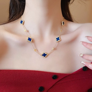 Detail of gold plated necklace featuring five blue clover charms on a delicate chain