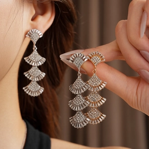 Detail of layered fan-shaped tassel earrings with rhinestones in gold and silver finish