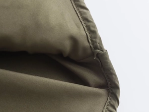 Détail de la texture en nylon vert olive avec coutures précises sur une veste à capuche