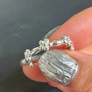 Close-up of minimalist 925 sterling silver ring with three delicate beaded flowers