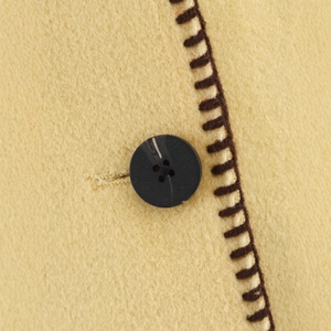 Close-up of ginger wool coat featuring textured fabric and dark buttons with hand-stitched detail