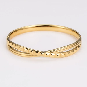 Polished gold knotted bangle featuring pyramid stud texture and a smooth mirror finish