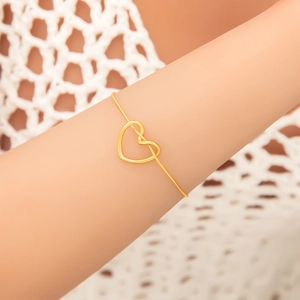 Close-up of minimalist gold titanium steel leaf bracelet featuring a hollow heart pendant