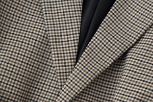 Macro detail of brown houndstooth blazer lapel with smooth black lining texture