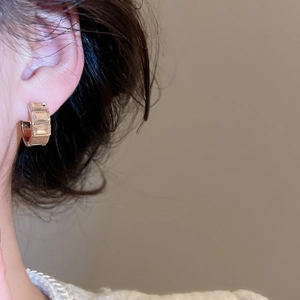 Close-up of elegant gold hoop earrings with baguette-cut zircons worn by a model