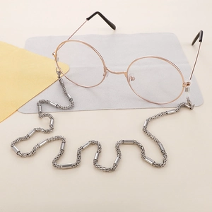 Polished silver stainless steel eyeglasses chain with non-slip rubber loops on beige surface