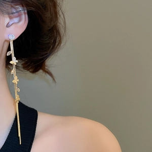 Détail de boucles d'oreilles longues à pampilles papillon et clous en zircon
